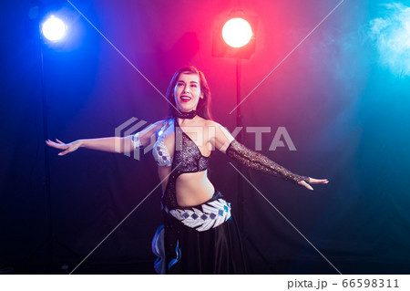 Girl dancing belly dance, fusion or tribal. A woman in a beautiful costume demonstrates charming and gentle movements in the dance. Girl dancing belly dance, fusion or tribal. A woman in a beautiful costume demonstrates charming and gentle movements in the dance. 66598311
