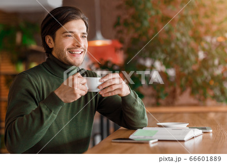 Enthusiastic guy freelancer having coffee break at cafe Enthusiastic guy freelancer having coffee break at cafe 66601889
