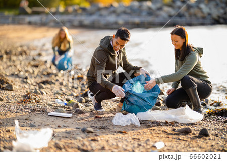 Team of dedicated and smiling volunteers collecting garbage at beach Team of dedicated and smiling volunteers collecting garbage at beach 66602021