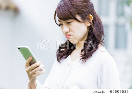 屋外でスマホを見るビジネスウーマン(不機嫌) 屋外でスマホを見るビジネスウーマン(不機嫌) 66602682