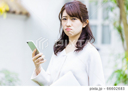 屋外でスマホを見るビジネスウーマン(不機嫌) 屋外でスマホを見るビジネスウーマン(不機嫌) 66602683