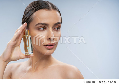 Calm young female using cosmetic treatment for face Calm young female using cosmetic treatment for face 66605846