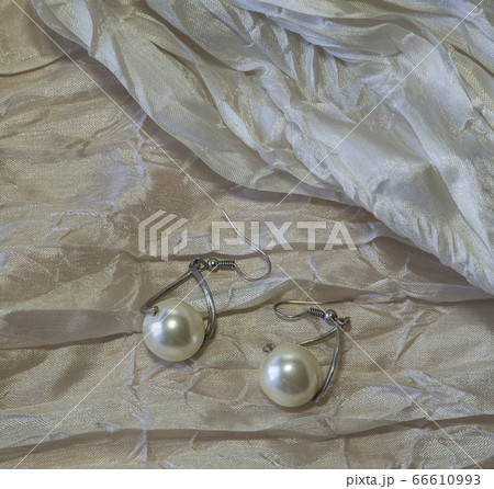 silver pearl earring on draped nacre background 66610993