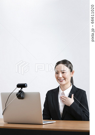 オンライン面接イメージ　ウェブカメラに向かって話すスーツ姿の若い女性 66611020