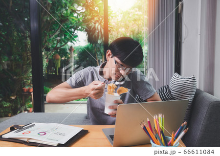 A man who works from home is busy talking on the phone and eating instant noodles. A man who works from home is busy talking on the phone and eating instant noodles. 66611084