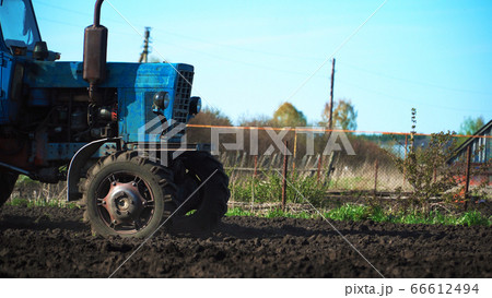 The tractor cultivates and cuts furrows in the The tractor cultivates and cuts furrows in the 66612494