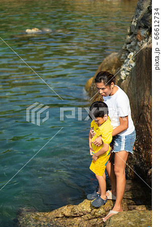 Mother and son watching the fish in the sea. Mother and son watching the fish in the sea. 66612734