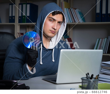 Young hacker hacking into computer at night 66612746