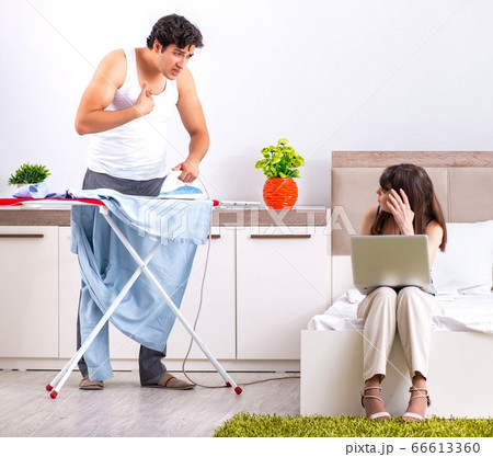 Man ironing, his lazy wife sitting 66613360