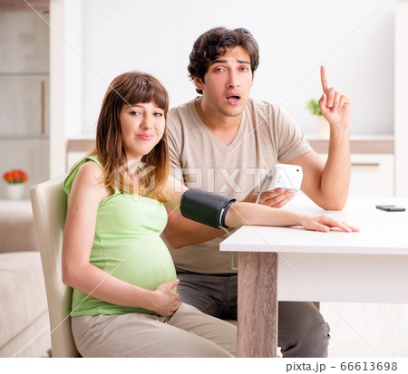 Husband checking pregnant wife's blood pressure Husband checking pregnant wife's blood pressure 66613698