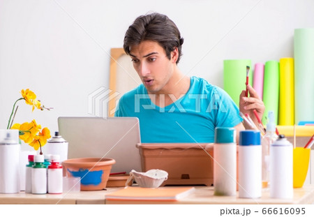 Young man decorating pottery in class 66616095