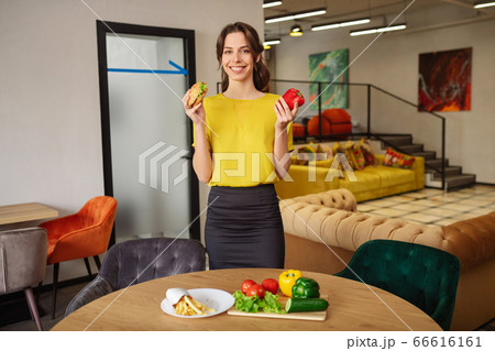 Pretty smiling woman with burger and red pepper. 66616161