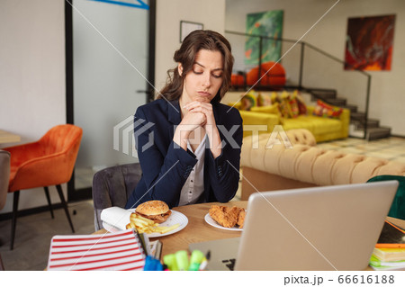 Thinking young woman sitting and looking at food in plates Thinking young woman sitting and looking at food in plates 66616188