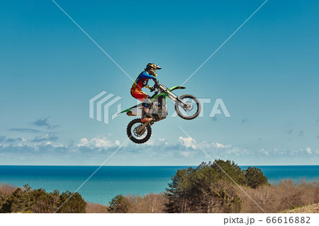 Motocross concept, a biker goes off-road making extreme skiing. In pursuit of adrinalin, sport concept. Dangerous sport. 66616882