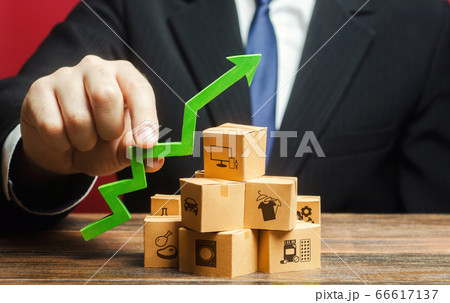 Businessman holding a green arrow up over boxes. Tactics and strategy, marketing. Value added goods. Boost sales rate. Increasing production of goods, expanding export opportunities, finding markets. 66617137