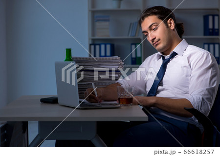 Alcohol addicted businessman working late in the office Alcohol addicted businessman working late in the office 66618257
