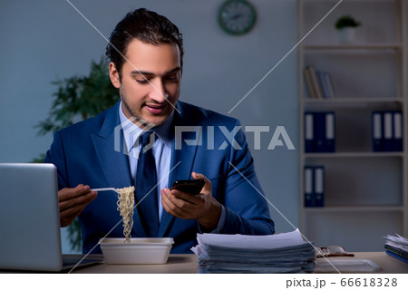 Hungry employee working late in the office Hungry employee working late in the office 66618328