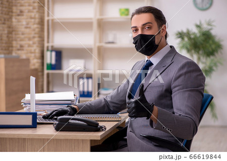 Young male employee in the office during pandemic disease 66619844