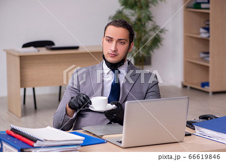 Young male employee in the office during pandemic disease 66619846
