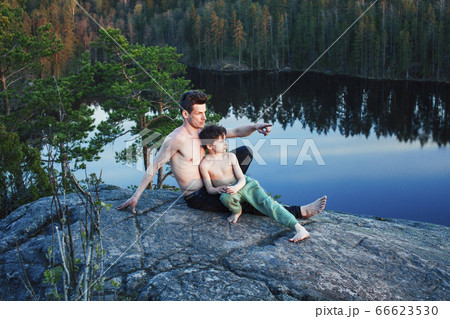 middle age man with little cute son doing sport yoga on the top of the mountain together, happy family lifestyle people outdoor, summer wild nature for training 66623530