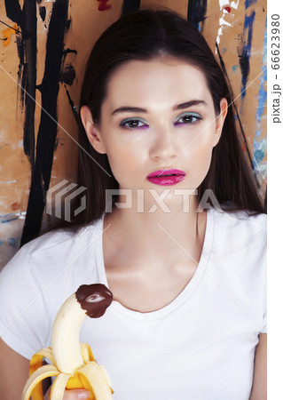 pretty brunette girl with banana and chocolate , fashion makeup on painted background pretty brunette girl with banana and chocolate , fashion makeup on painted background 66623980