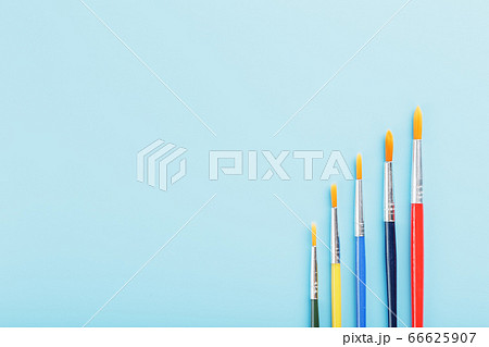 Multi-colored paint Brushes on a blue background. Multi-colored paint Brushes on a blue background. 66625907