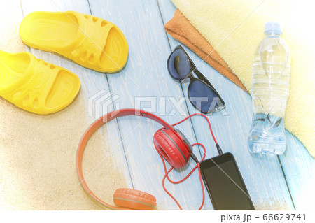 Bottle of water and bright towels, yellow slate on blue background and sunglasses. Copy Space. 66629741