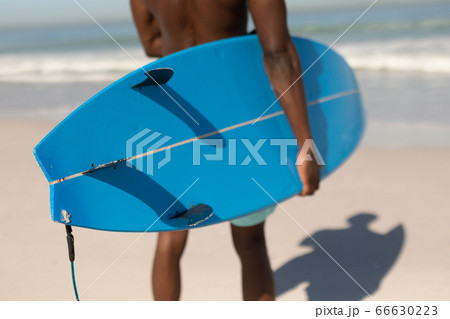 African American man holding surf board on the beach 66630223