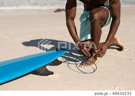 African American man and surf board on the beach 66630235