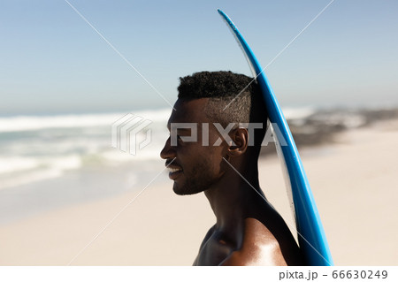 African American man holding surf board on the beach African American man holding surf board on the beach 66630249