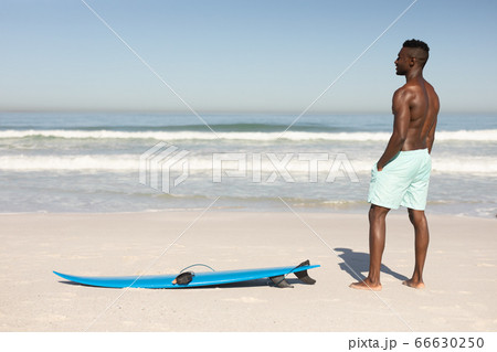 African American man and surf board on the beach 66630250