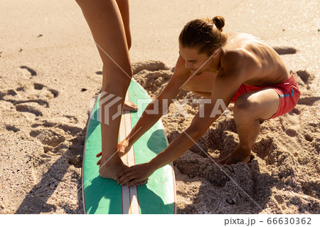 Young mixed race people practising surf on beach 66630362