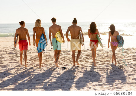 Young mixed race people holding surf boards on beach 66630504