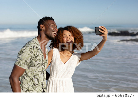 Happy couple taking a selfie on the beach 66630577