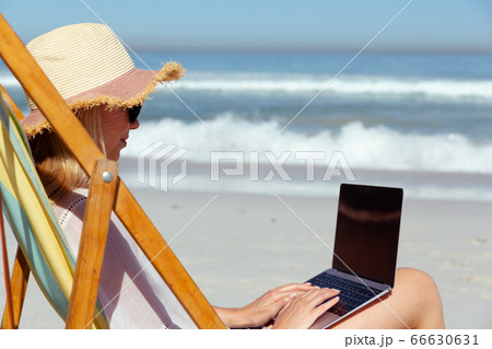 Caucasian woman using her laptop seaside Caucasian woman using her laptop seaside 66630631