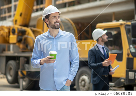 Foreman holding coffee cup, building supervisor standing behind him with tablet 66639505