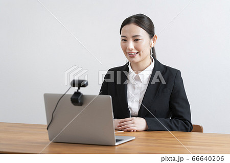 オンライン面接イメージ　ウェブカメラに向かって話すスーツ姿の若い女性 66640206