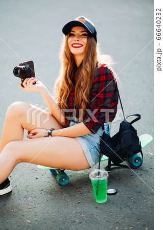Hipster girl sitting on skateboard and taking Hipster girl sitting on skateboard and taking 66640232