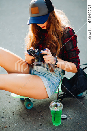 Hipster girl sitting on skateboard and taking Hipster girl sitting on skateboard and taking 66640233