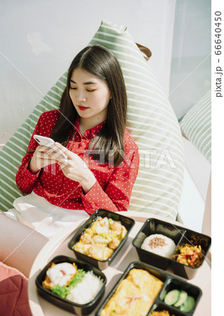 Woman texting on the phone before eating food. 66640450