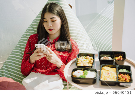 Woman texting on the phone before eating food. 66640451