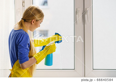 Woman cleaning window at home 66640584