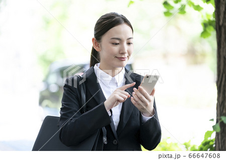 スマートフォンを操作するスーツ姿の若い女性 66647608