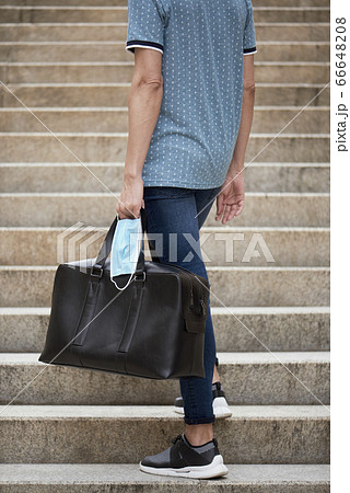 man carrying a travel bag and a surgical mask man carrying a travel bag and a surgical mask 66648208