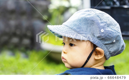 帽子をかぶった子供の横顔のアップと緑バック 66648479