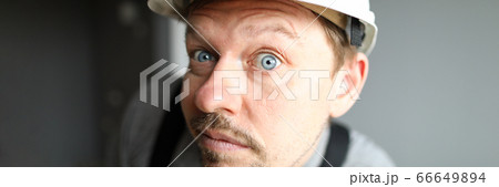 Surprised man in helmet looks closely and listens Surprised man in helmet looks closely and listens 66649894