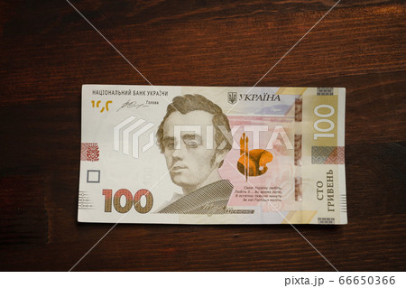 New Ukrainian money. Paper one hundred hryvnia notes with famous Ukrainian historical figure, artist and poet Taras Shevchenko on it. High angle view 66650366