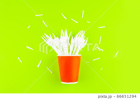 Broken plastic forks in a plastic cup instead of a bouquet of flowers on a green background. Broken plastic forks in a plastic cup instead of a bouquet of flowers on a green background. 66651294