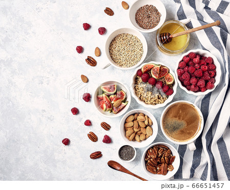 Healthy breakfast, top view. Oatmeal porridge with raspberries, figs, chia seeds, flax seeds, almonds and pecans, honey and coffee. Healthy breakfast, top view. Oatmeal porridge with raspberries, figs, chia seeds, flax seeds, almonds and pecans, honey and coffee. 66651457