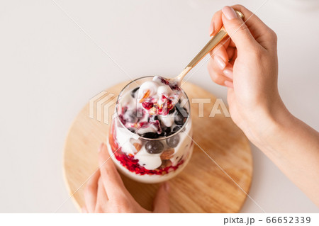 Hand of girl with teaspoon of fresh appetizing homemade yoghurt over glass Hand of girl with teaspoon of fresh appetizing homemade yoghurt over glass 66652339